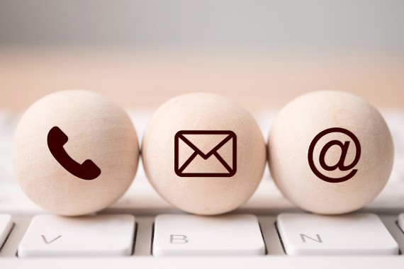 Trois boules sur un clavier affichent des symboles de téléphone, de courriel et d’arobase